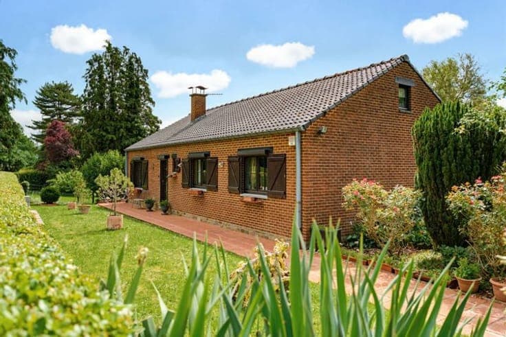 A single-story house located in a lush, green setting