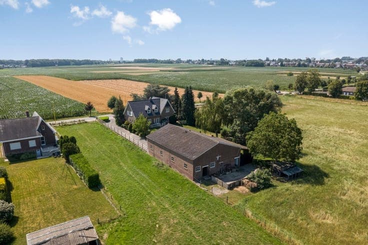 Villa met grote loods, omgeven door groen